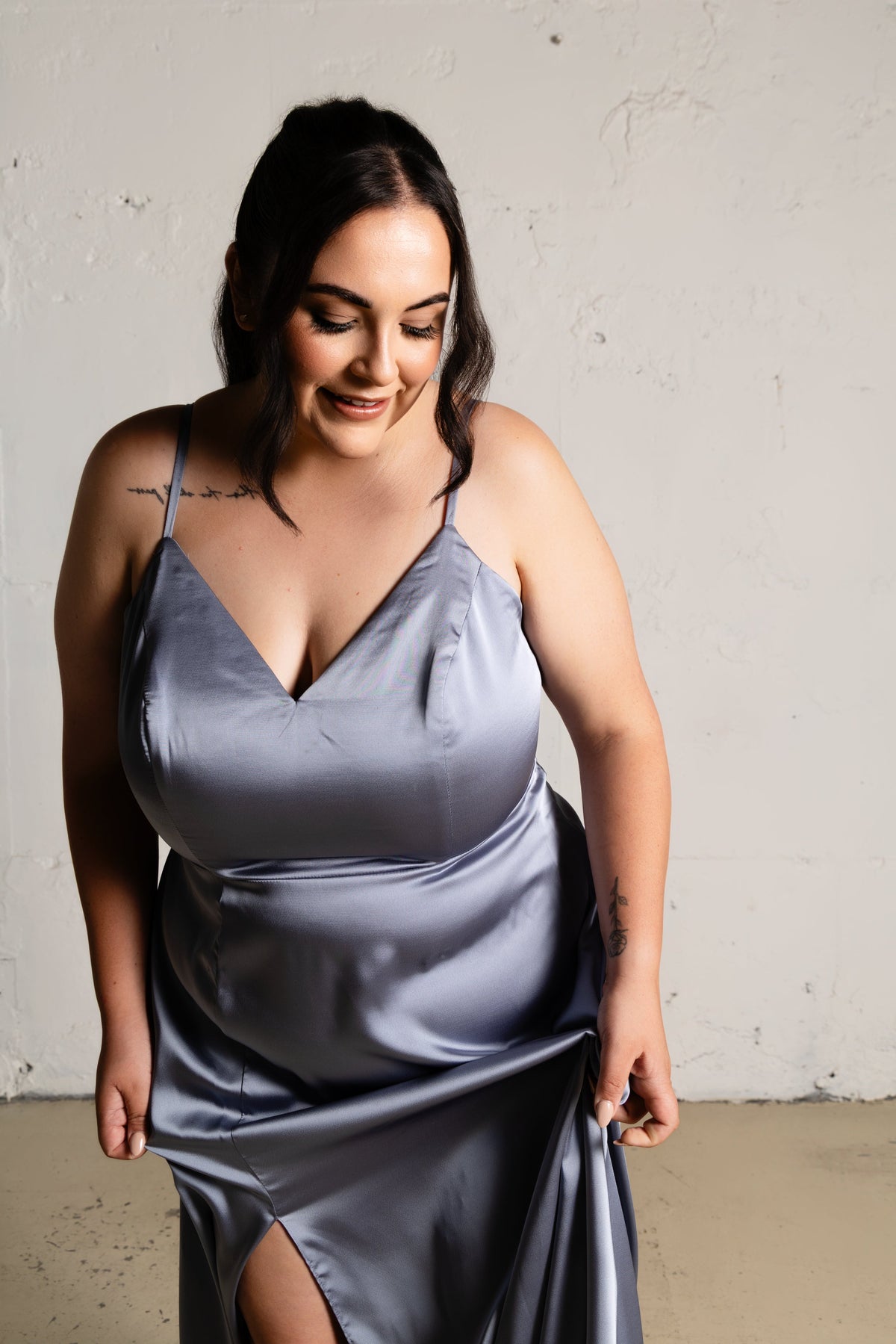 Woman wearing a gray satin slip dress against a plain background