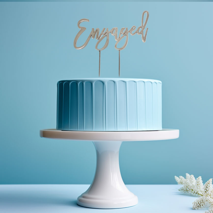 Gold "Engaged" cake topper from Cake and Candle giftware, featuring elegant design for wedding or engagement celebration.